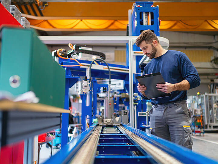 Industrial worker with a clipboard checking the components of a large industrial machine